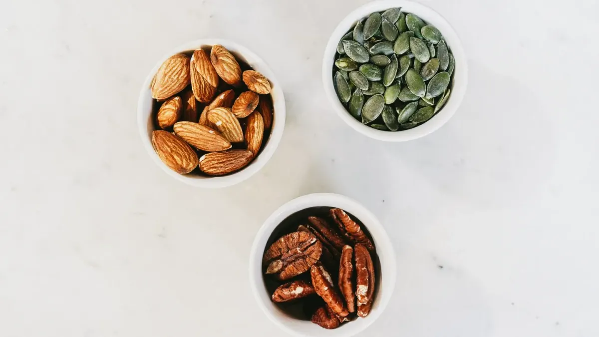 A bowl of mixed nuts sitting on a kitchen counter while a dog watches nearby