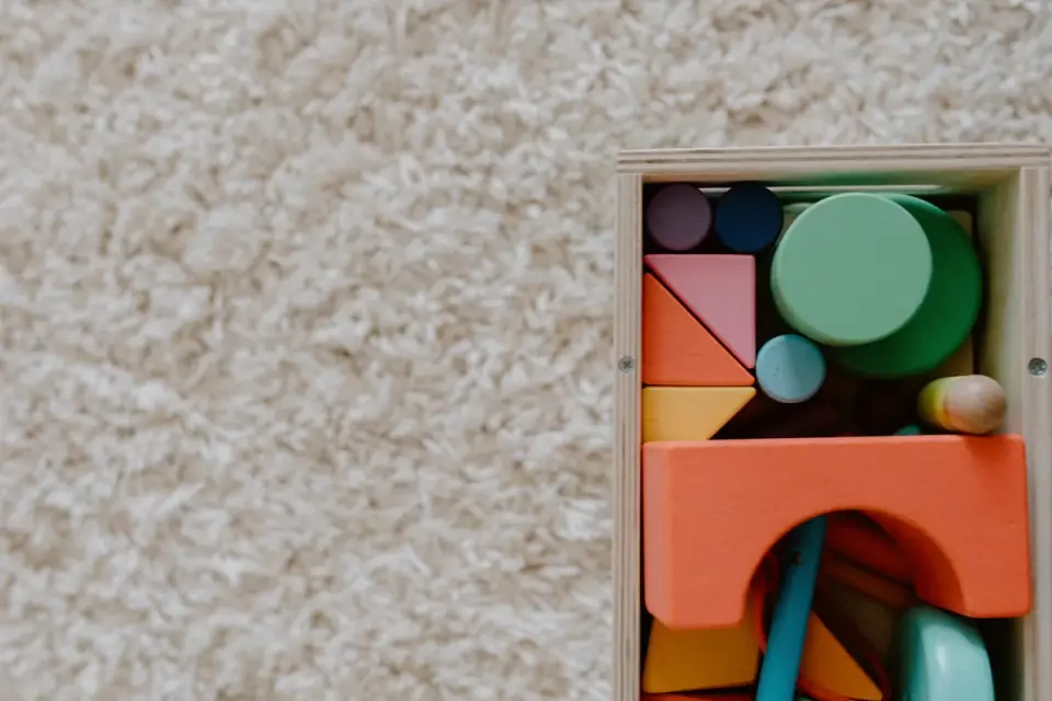 A dog rolling a treat-dispensing puzzle toy across a rug