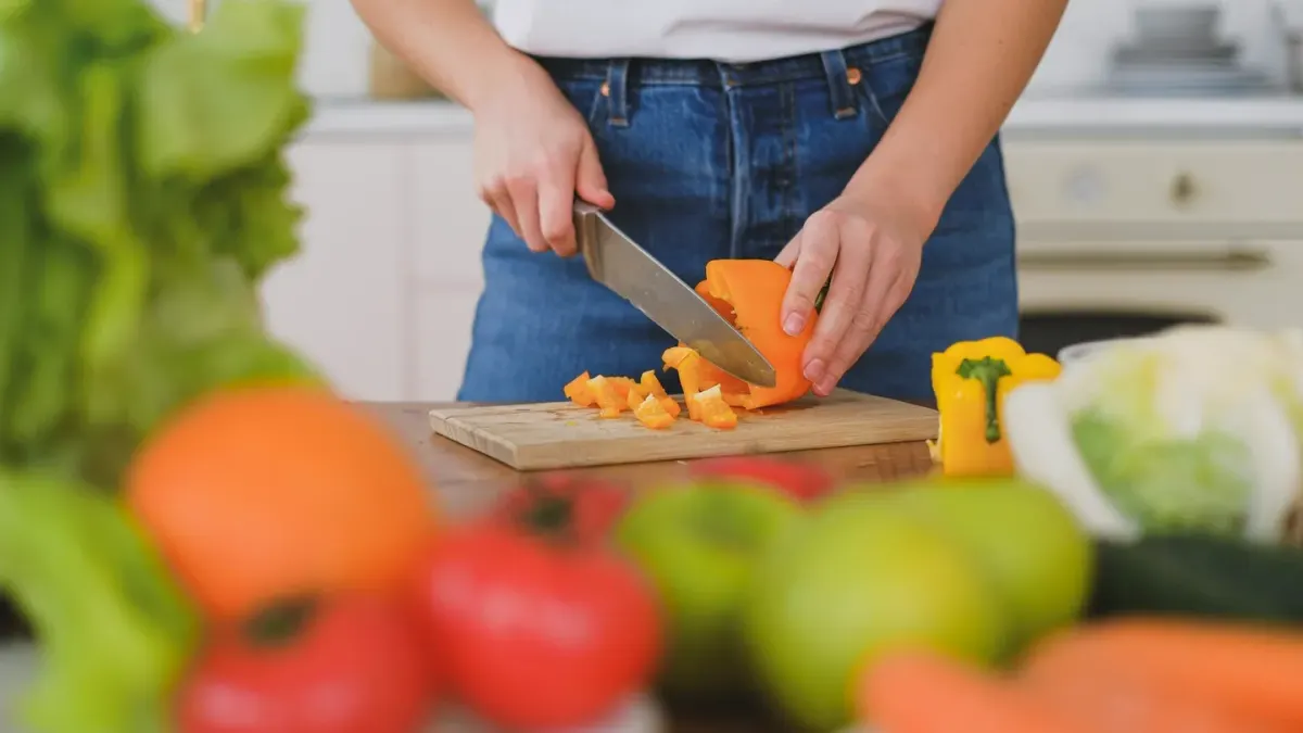 A dog sniffing a hand holding sliced carrot pieces in a kitchen
