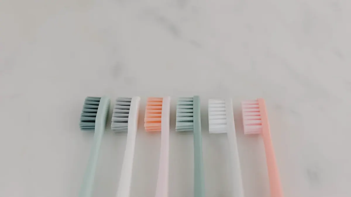 A dog toothbrush resting next to a tube of pet toothpaste on a counter