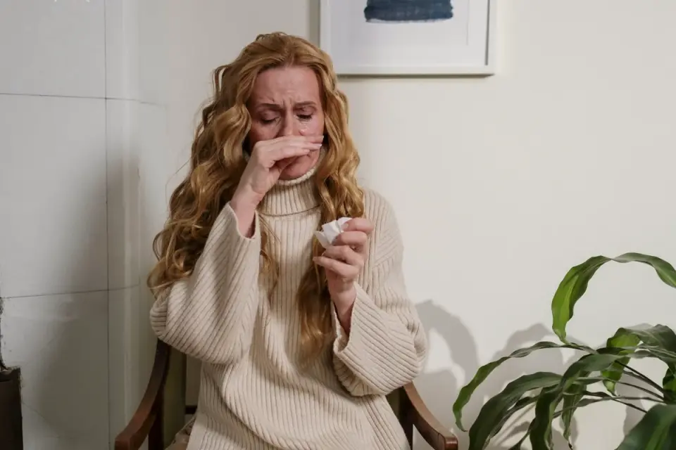 A person with allergy symptoms sitting near a dog on a couch