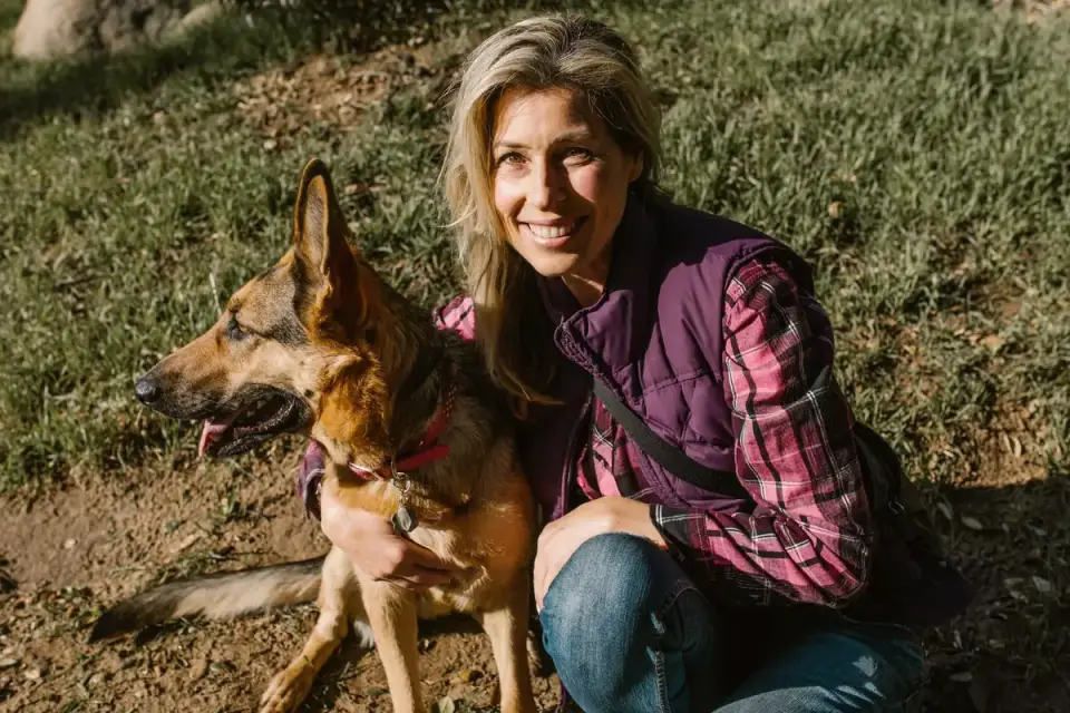 A relaxed dog leaning against its owner outdoors, showing settled body language