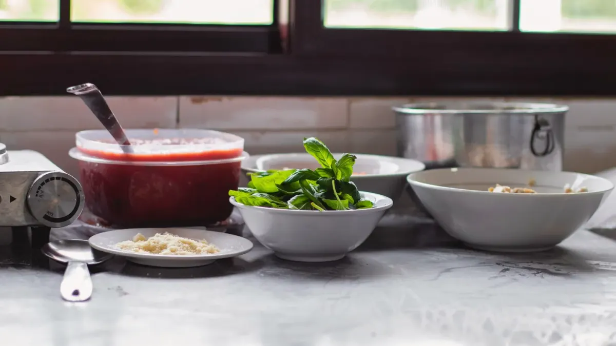 A stainless steel dog bowl holding wet food set on a kitchen floor