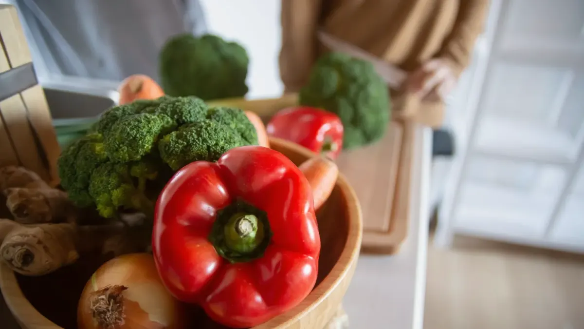 Chopped broccoli florets beside a stainless steel dog bowl on a kitchen counter