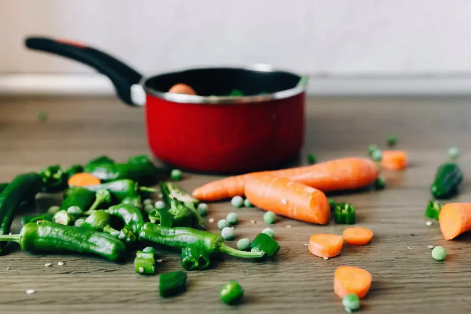 Sliced carrot coins next to dog treats on a wooden cutting board