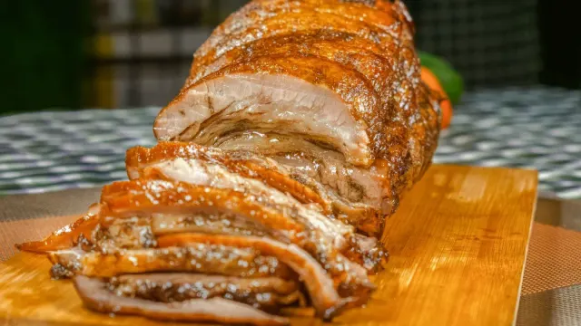 Sliced roast turkey breast on a wooden cutting board with a dog watching a few feet away
